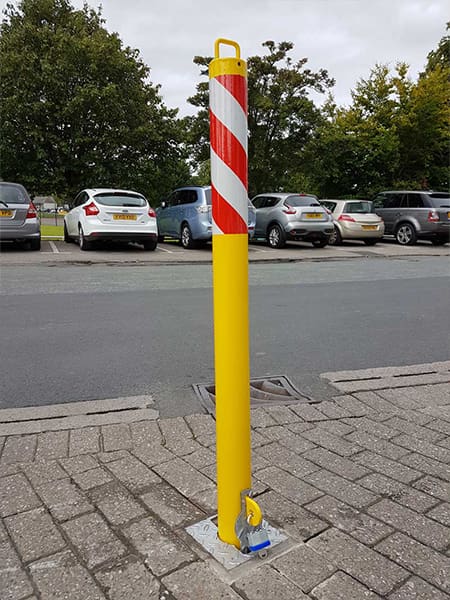 Removable steel security bollard in an urban setting, providing temporary vehicle restriction.